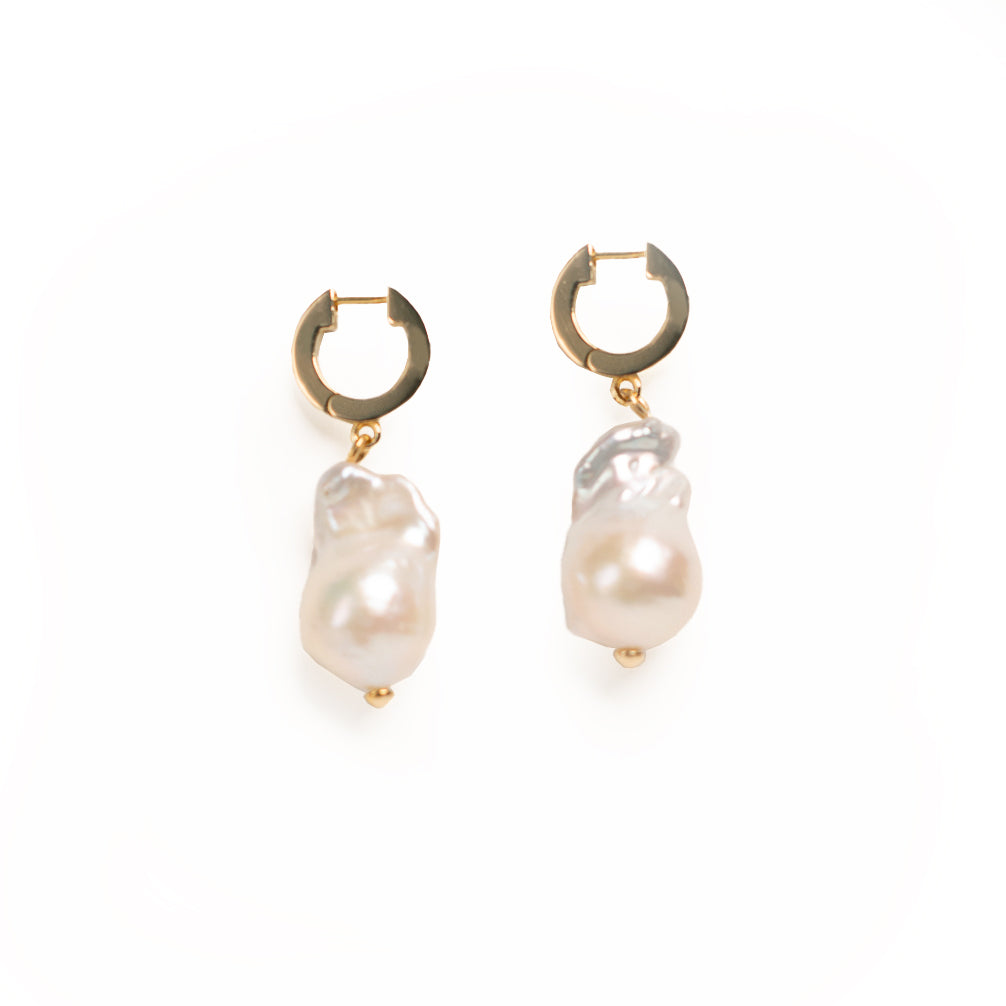 Pair of baroque pearl dangle earrings with gold huggie hoop components on a white background