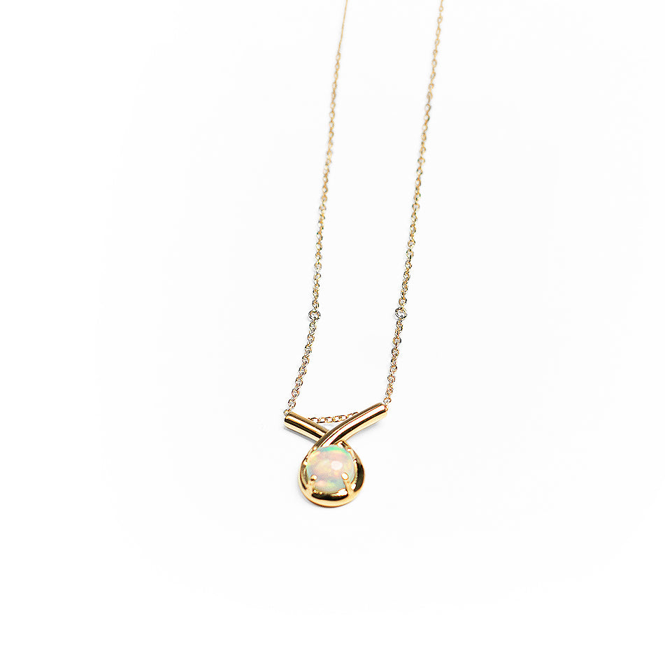 Gold loop pendant necklace with a white opal on a white background