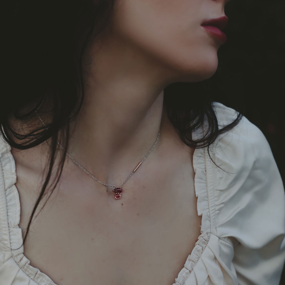 Close-up of a woman wearing a delicate necklace in two tone white and rose gold with a small pink tourmaline and pink garnet rose gold pendant