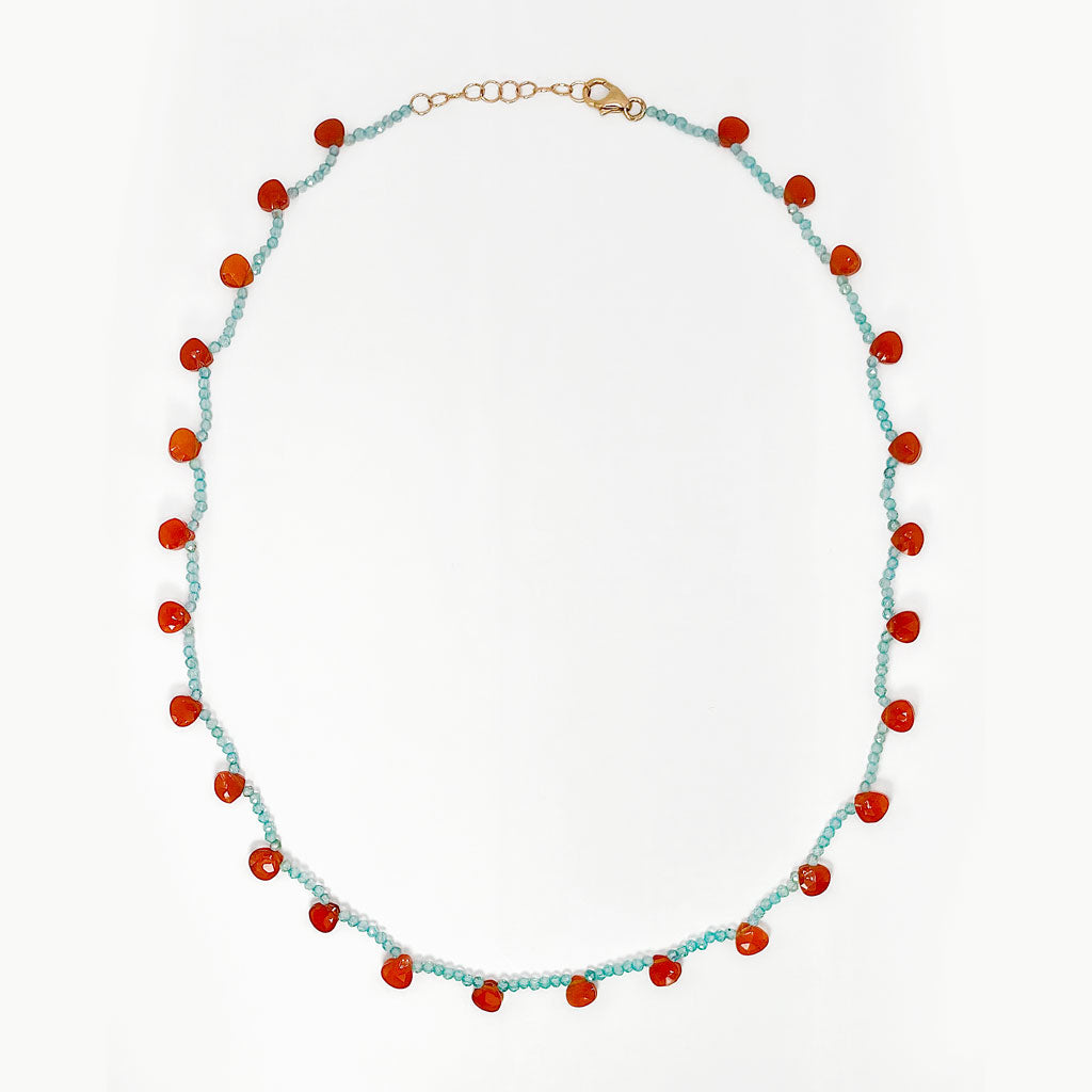 A beaded necklace featuring light blue apatite gemstone beads and alternating translucent orange-red pear shaped carnelian gemstone beads, finished with a 14K rose gold clasp, shown on a plain white background.