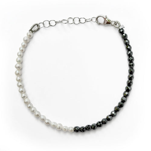 A split-color beaded bracelet featuring one half with white faux pearls and the other half with faceted dark gray beads, connected by a silver-tone chain and lobster clasp, shown on a plain white background.