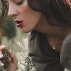 woman wearing 14k yellow gold loopy ethiopian opal necklace holding a pine tree branch in a forest setting