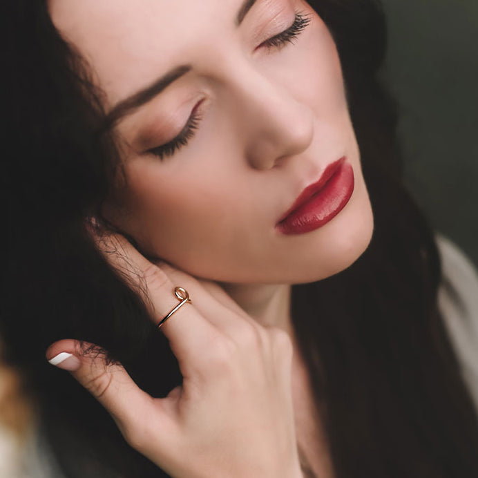 Close-up of a woman wearing a gold ring on her finger with a blurred background