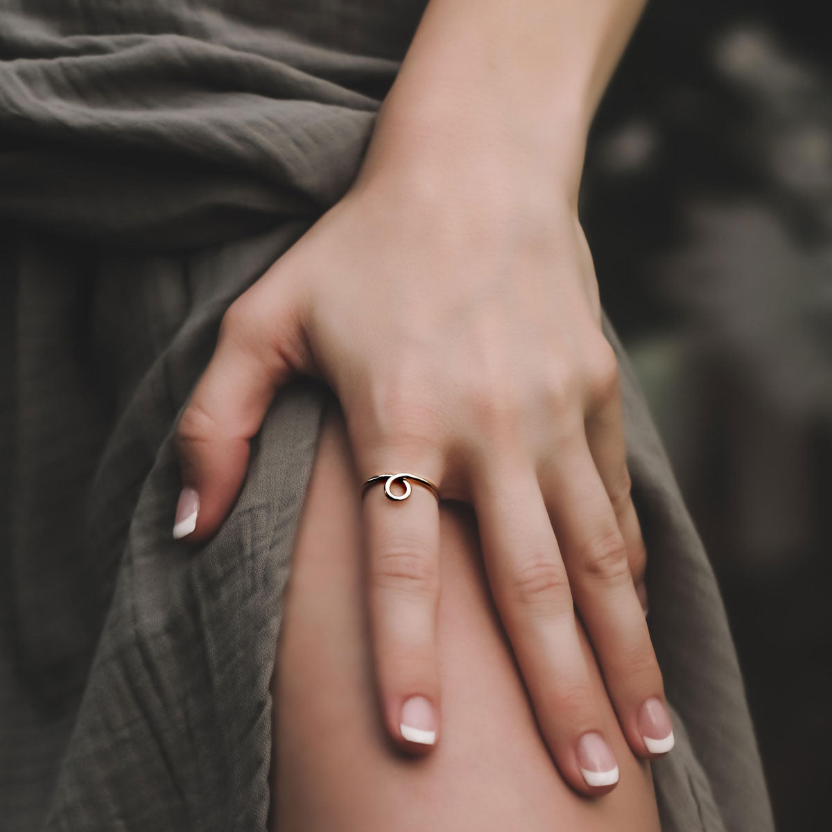 hand wearing 14k gold loopy ring with a blurred background