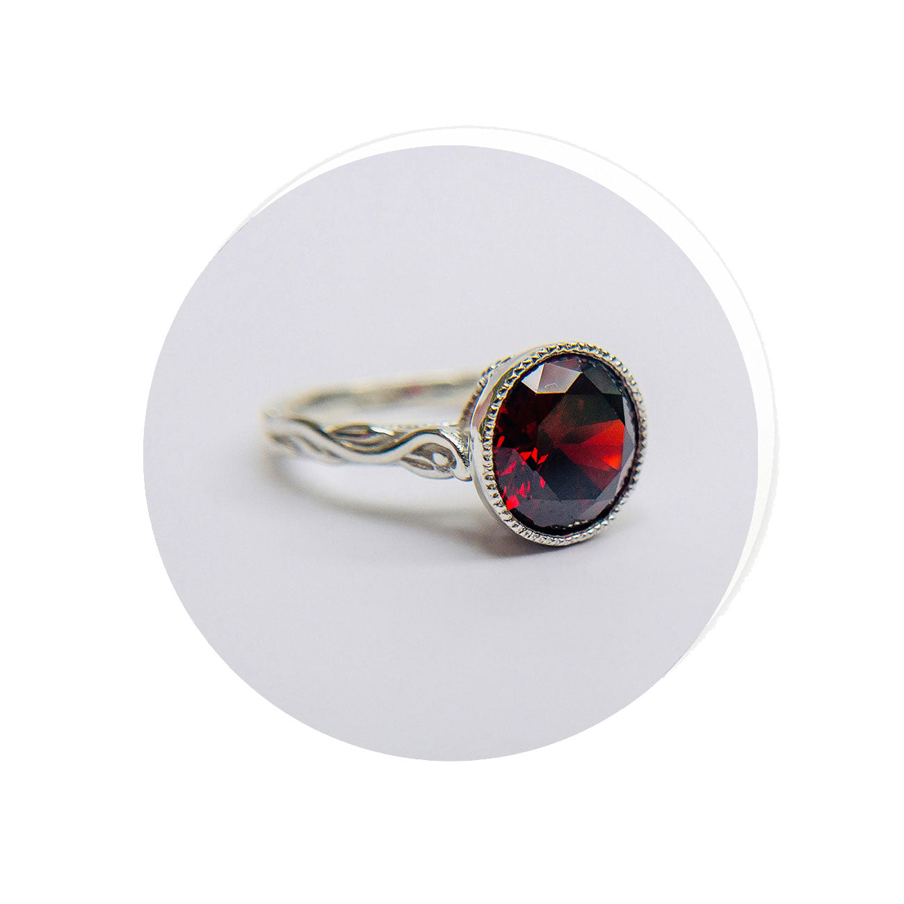 Silver ring with a red Mozambique garnet gemstone on a white background