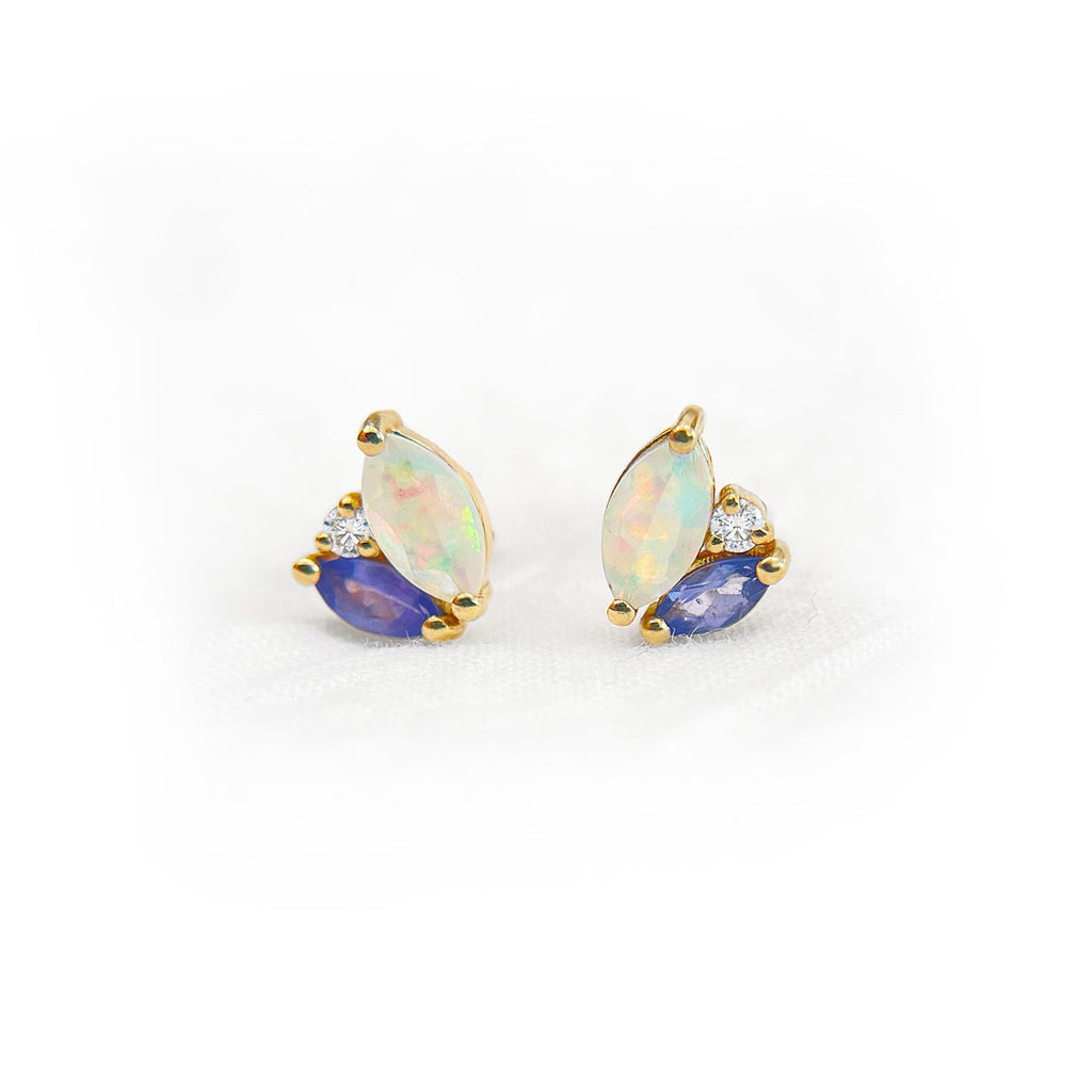 Pair of earrings with opal and tanzanite gemstones accented by diamonds on a white background