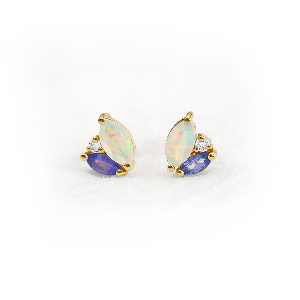 Pair of earrings with opal and tanzanite gemstones accented by diamonds on a white background