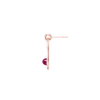 Rose gold hoop earring with a reddish pink garnet gemstone on a white background side view
