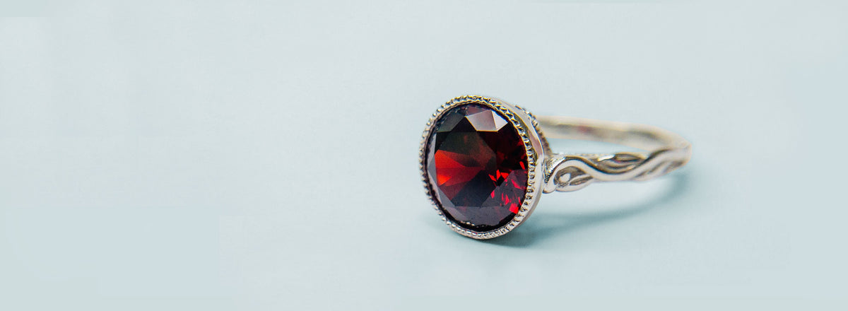 Silver ring with a red gemstone on a light blue background