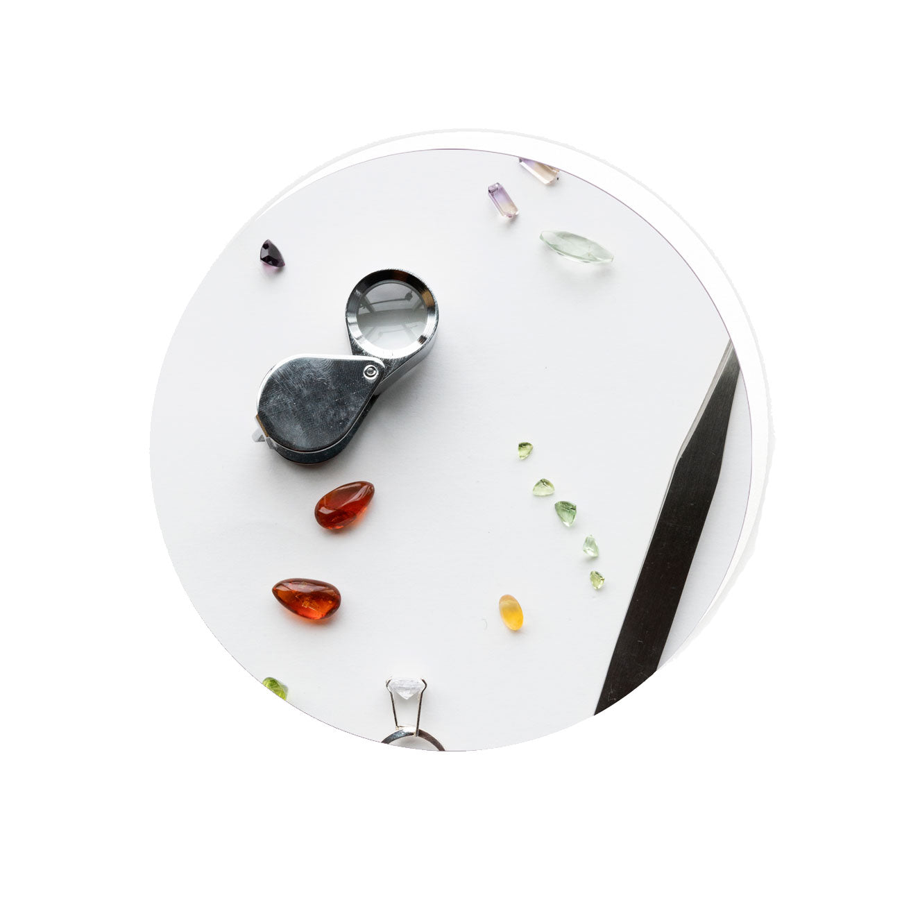 Round white surface with gemstones and a loupe on a white background