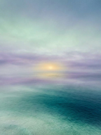A minimalist seascape photograph featuring calm, textured blue-green water under a pale blue and white hazy sky, with a faint sailboat visible on the horizon.